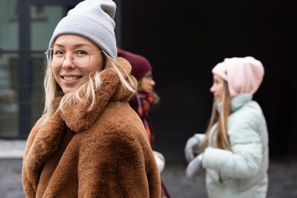 A woman in a comfy winter coat taking a picture near her two friends.